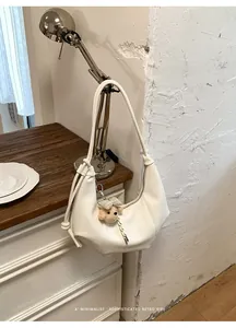 Detailed view of white pleated hobo bag hanging on a vintage desk lamp.