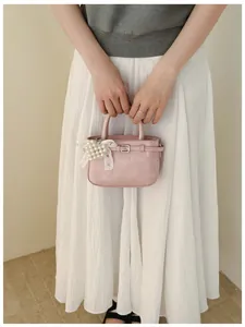 Elegant pink leather handbag with pearl heart charm and lace ribbon for women's fashion.