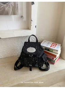 Close-up of small black canvas backpack with white star patterns in academic setting