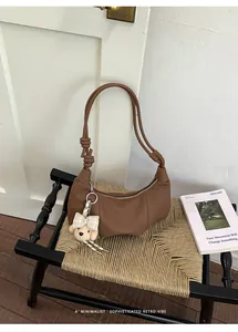 Elegant retro brown pleated hobo underarm bag with cute bear charm displayed on a vintage chair