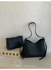 Detail einer schwarzen gewebten Hobo-Tasche und passenden Tasche in minimalistischem Stil.