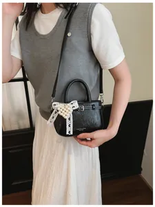Detailed view of stylish black textured mini handbag with pearl heart lace bow