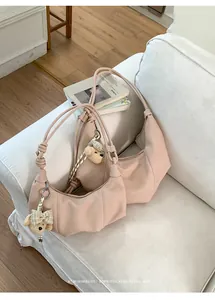 Close-up of minimalist retro pleated shoulder bags with cute bear charms in apricot