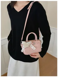 Close-up detail of a pink mini crossbody bag featuring a pearl heart bow and buckle.
