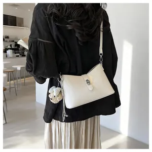 Cream retro faux leather shoulder bag featuring a plush bear charm and metallic lock.