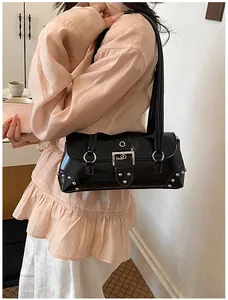 Bolso de hombro negro con hebilla plateada y tachuelas mostrado en modelo.