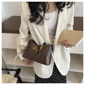 Detail view of an elegant vintage brown leather shoulder bag worn with a white blazer