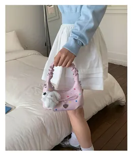Dettaglio di una borsa a mano rosa increspata con ciondolo a coniglio e stelle.