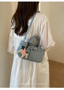 Vista dettagliata di una borsa tote in pelle blu con ciondolo a forma di pony