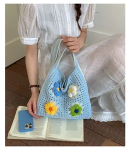 Detailed view of a handmade blue crochet tote bag featuring colorful 3D flower decorations