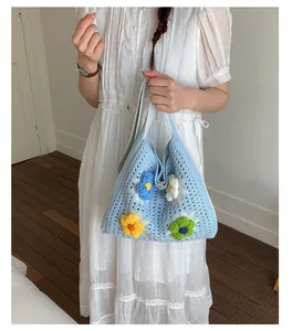 Detail of light blue crochet tote bag with colorful knitted flowers worn by a model