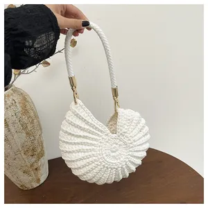 Close-up of a white shell-shaped woven handbag with elegant golden hardware details.