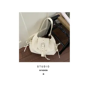 Close-up of a retro cream nylon hobo bag with silver buckle and drawstring details.
