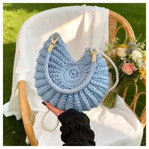 Detailed view of light blue woven conch bag with pearl strap and golden hardware