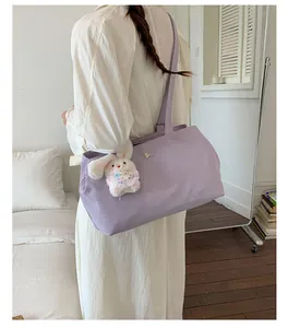Detailed view of lightweight lavender nylon tote bag with a cute bunny charm carried by model
