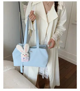 Close-up detail of a lightweight blue nylon tote bag featuring a cute plush bunny charm