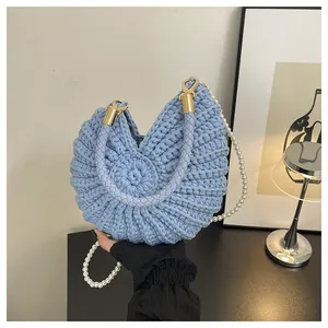 Detailed close-up of light blue hand-woven shell-shaped bag with elegant pearl strap