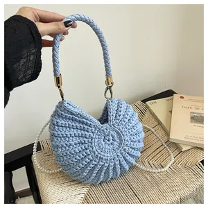 Detailed view of a light blue woven conch shell handbag with elegant pearl strap