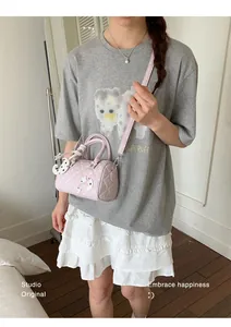 Vue détaillée d'un sac bandoulière Boston rose à pois porté par un mannequin élégant.