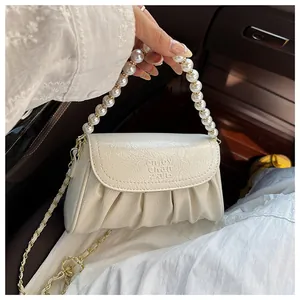 Vista dettagliata di un'elegante borsa a pieghe bianca con manico in perle grandi