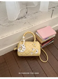 Vue rapprochée d'un sac Boston jaune matelassé à pois avec des breloques célestes.
