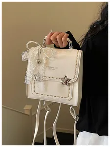 Dettaglio dello zaino bianco con fiocco in pizzo e perle e accenti metallici a stella.