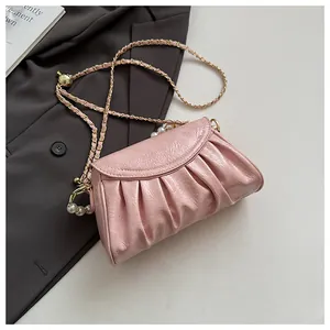 Primo piano della borsa a tracolla plissettata rosa con elegante catena di perle e oro.