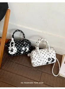 Détail des sacs boston à pois noirs et blancs avec des breloques étoile et lune