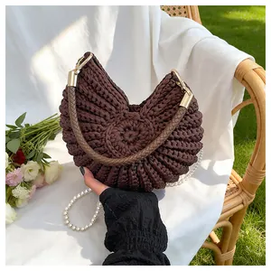 Detail view of brown crochet shell bag with pearl strap on a white cloth background.