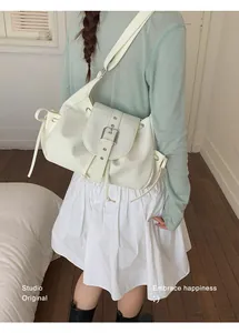 Cream white retro nylon underarm bag worn by model in a bright, minimalist studio setting