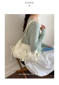 Side view of white nylon hobo bag worn by model in minimalist indoor setting