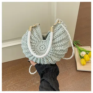 Detail of mint green conch-shaped woven bag with pearl strap and braided handle