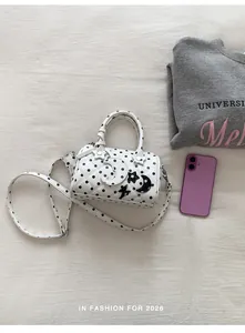 Gros plan d'un sac Boston à pois blancs avec breloques étoile et lune dans un décor