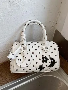 Sac Boston matelassé blanc à pois noirs avec breloques étoiles et lunes élégantes.