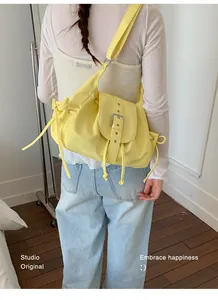 Detailed shot of a stylish yellow nylon shoulder bag featuring buckle and drawstring accents