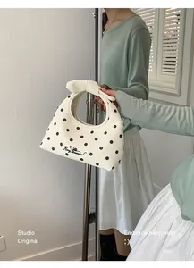 Primo piano di una mini borsa bianca a pois neri con un manico rotondo molto elegante