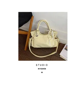 Detailansicht einer cremefarbenen Ledershopper-Tasche mit Schleife und Herzanhänger