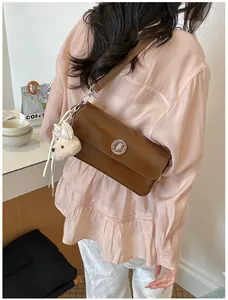 Vintage brown leather crossbody bag with silver circular buckle and plush bear charm
