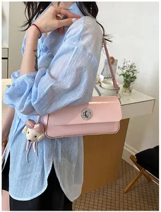 Detailed view of a vintage pink rectangular shoulder bag with a bear charm on a model