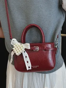 Elegant red wrinkled leather handbag featuring a white lace bow and pearl charm