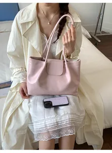 Detail view of a stylish pink pleated tote bag with flap closure held by a female model.