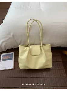 Light yellow pleated shoulder tote bag displayed on a cozy wooden floor setting