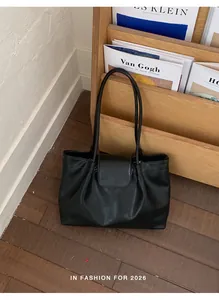 Detailed view of a large black pleated leather tote bag in a minimalist setting