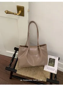 Detailed view of a large tan pleated tote bag resting on a vintage woven chair