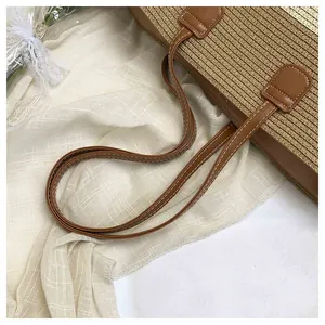 Detailed view of handmade woven straw tote bag with durable brown faux leather straps