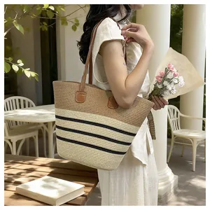 Elegant handmade woven straw tote bag with striped pattern being worn by a model
