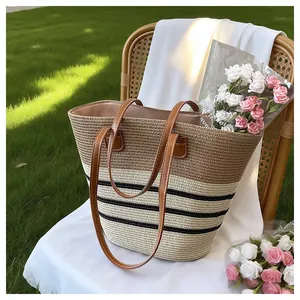 Handmade woven straw tote bag with brown leather handles and stripes in outdoor setting