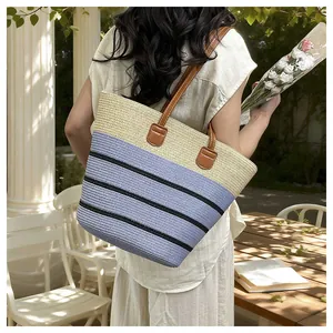Hand-woven straw beach tote bag with purple color-block and stripes on a model