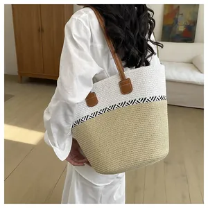 Detailed side view of a stylish two-tone woven straw tote bag on a model's shoulder