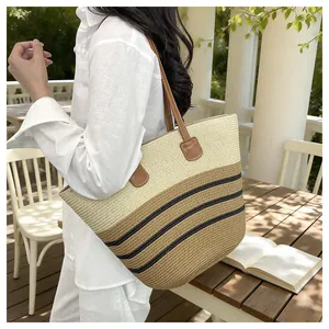 Stylish striped woven straw beach tote bag worn by a model in a bright outdoor setting
